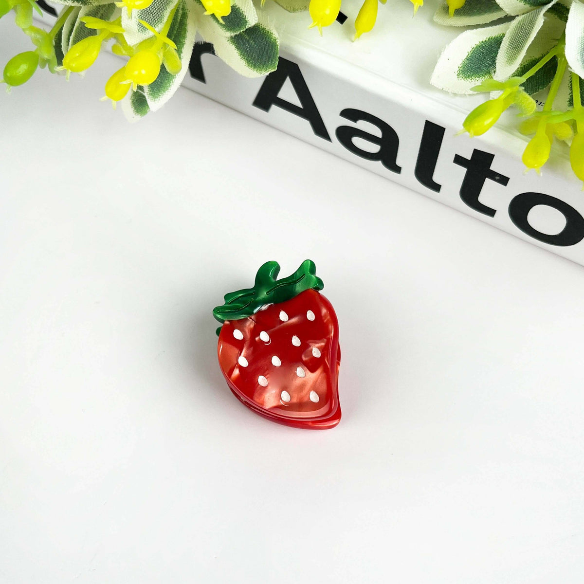 Strawberry hair clip in vibrant red acetate with polka dots and green leaf, perfect for playful hairstyles.