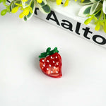 Strawberry hair clip in vibrant red acetate with polka dots and green leaf, perfect for playful hairstyles.