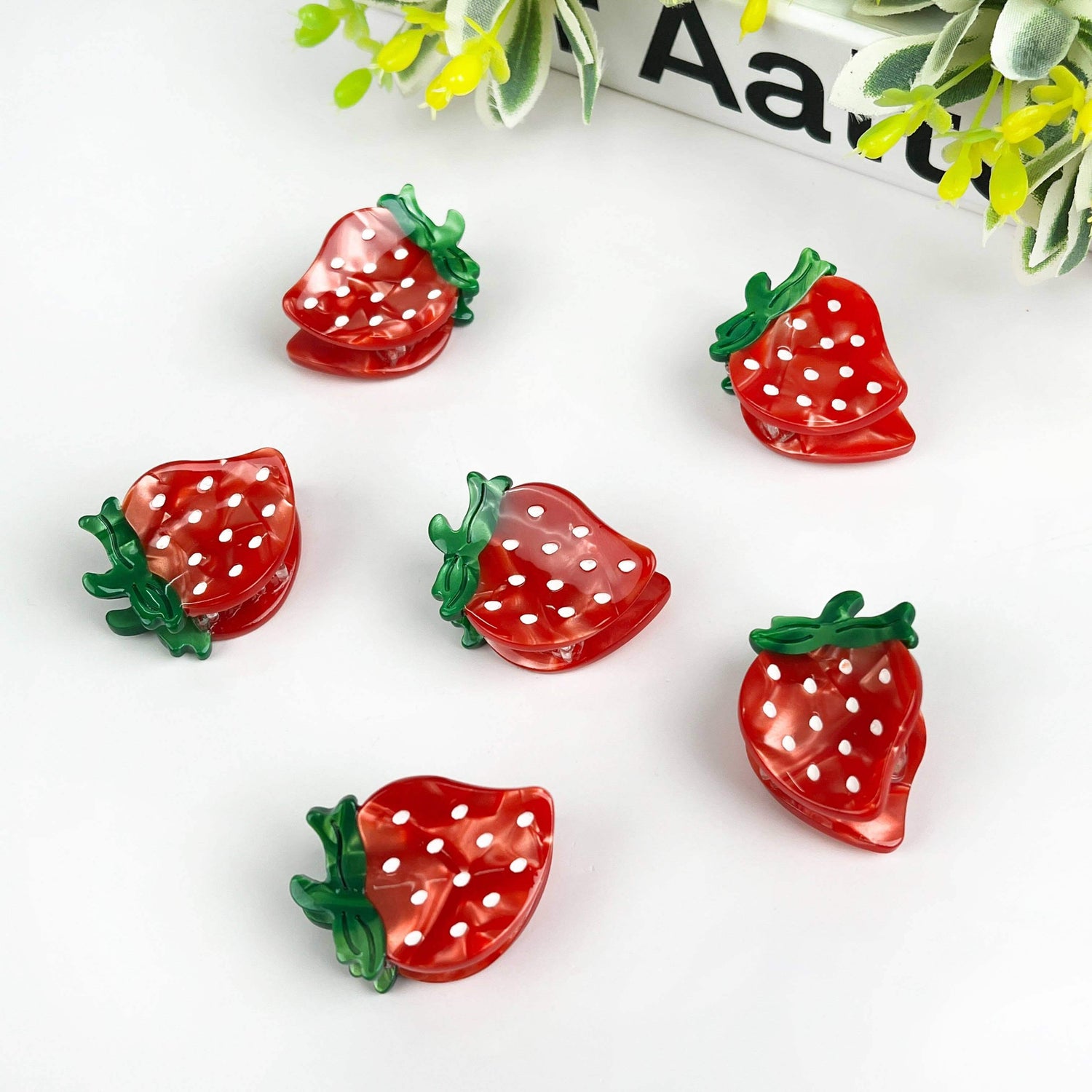 Set of colorful strawberry hair clips featuring vibrant red and green polka dot designs, ideal for fun hairstyles.