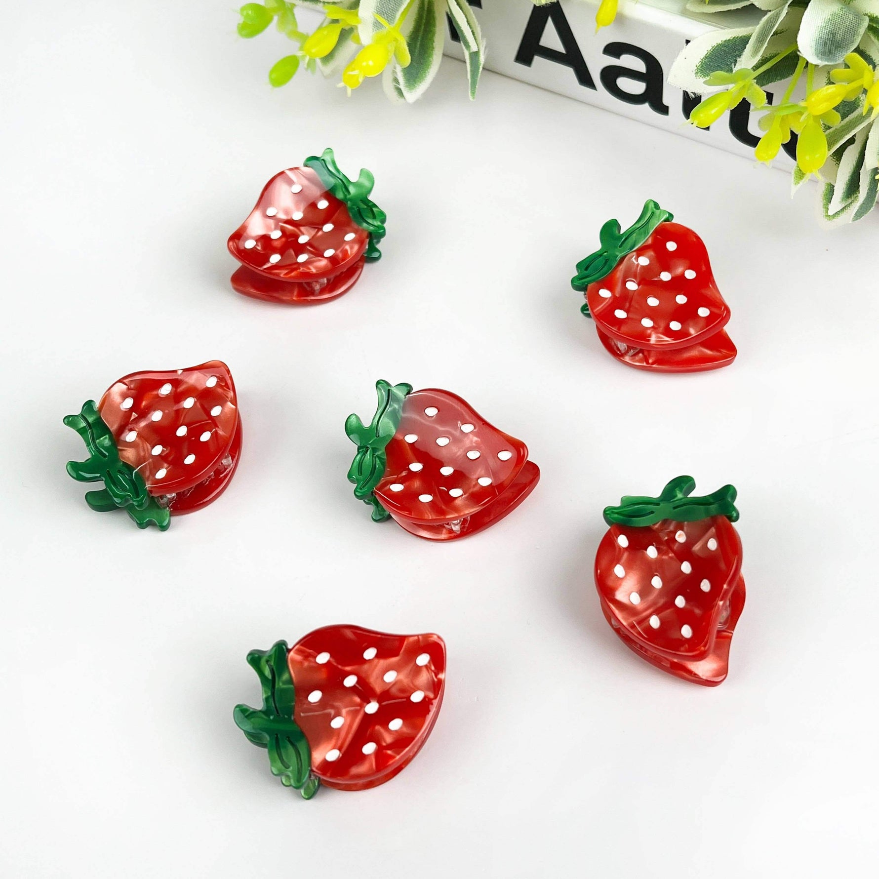 Set of colorful strawberry hair clips featuring vibrant red and green polka dot designs, ideal for fun hairstyles.
