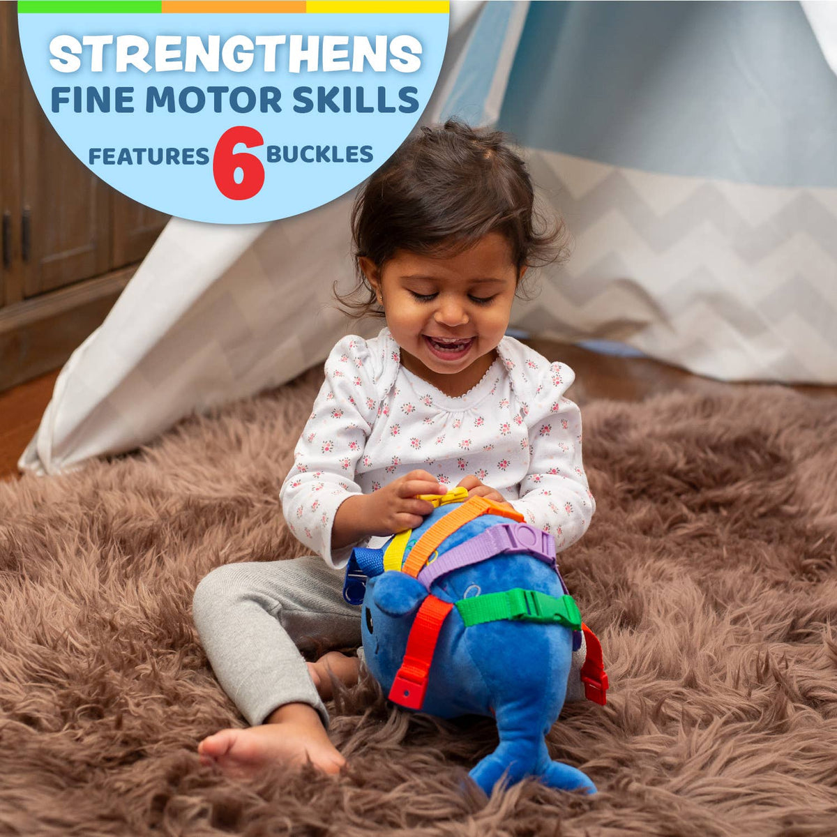 Child playing with the blue baby sensory whale toy while sitting on the floor.