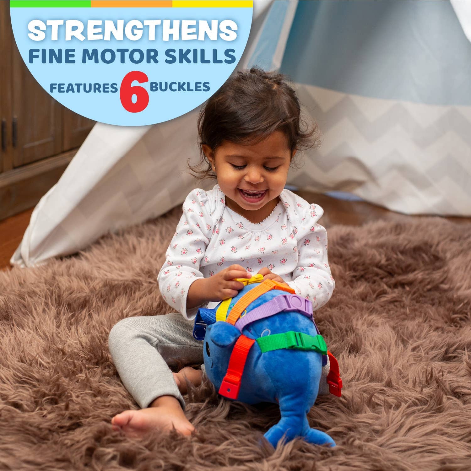 Child playing with the blue baby sensory whale toy while sitting on the floor.